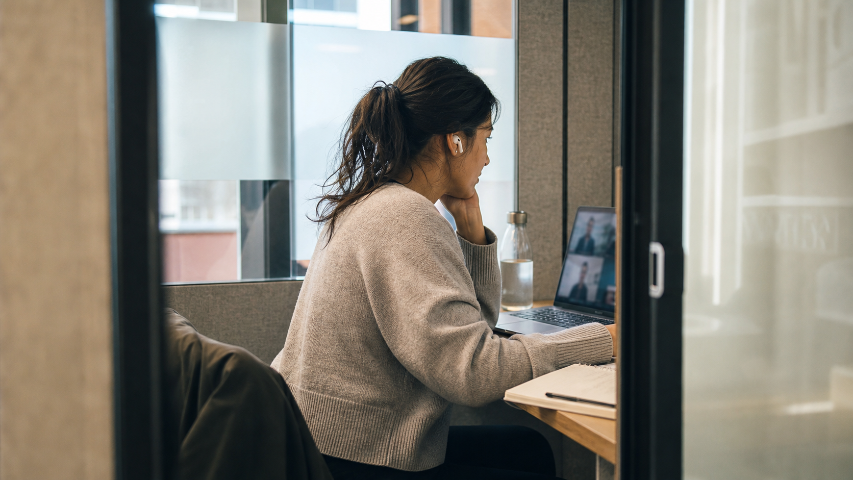 Woman on a video call with AirPods in, listening, in a quiet office pod